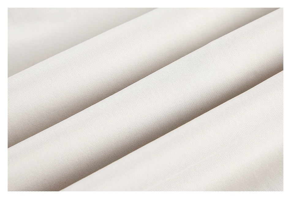 Close-up of the fine diagonal texture on light ivory trouser fabric.
