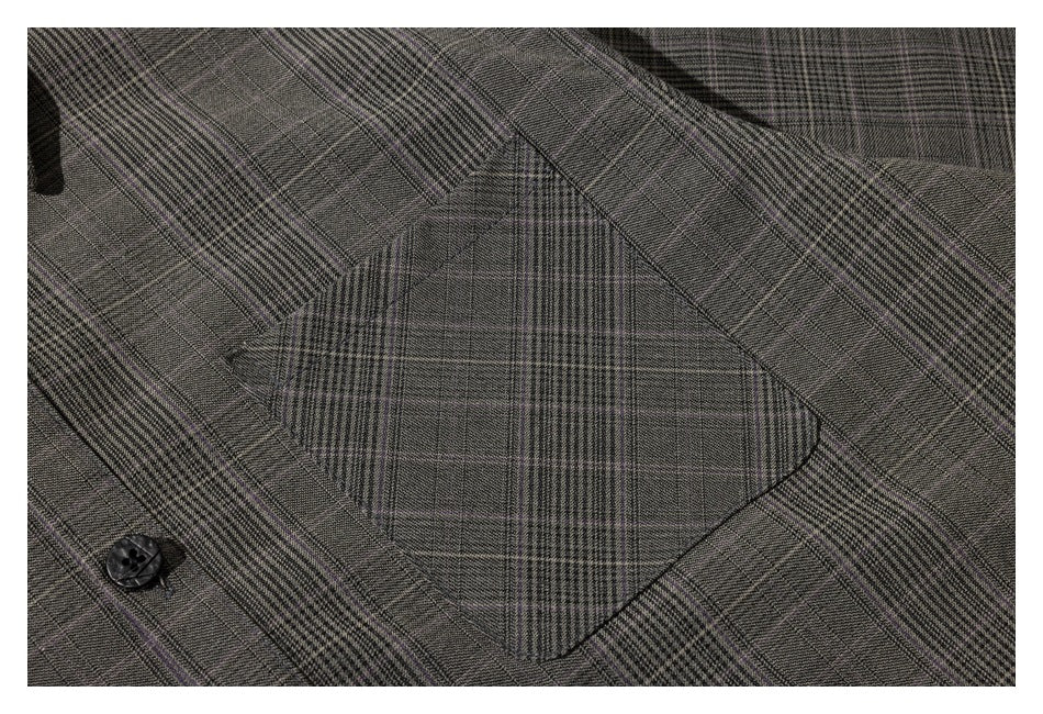 Close-up of the gray plaid shirt's matching-pattern chest pocket and a black button.
