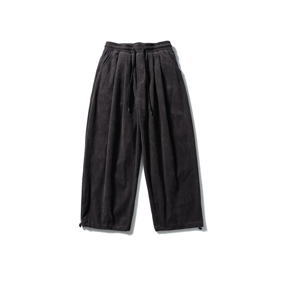 Dark gray corduroy wide-leg pants with drawstring elastic waist, front pleats and hem toggles, flat lay front view