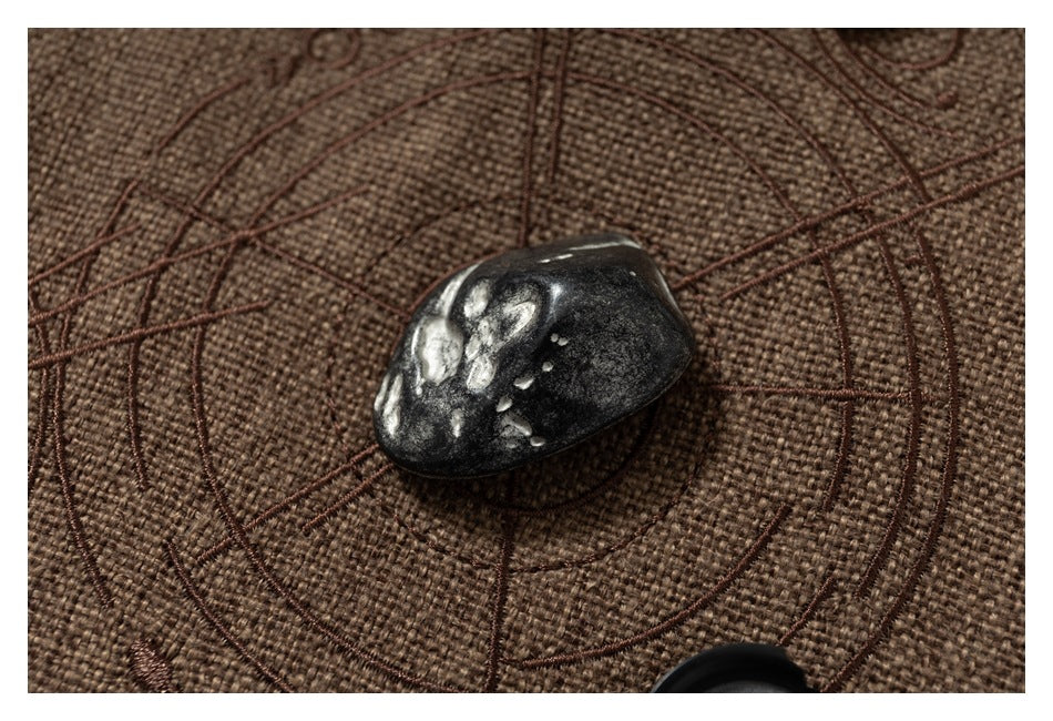 Close-up of a glossy dark button on brown textured fabric, with part of another button visible below.