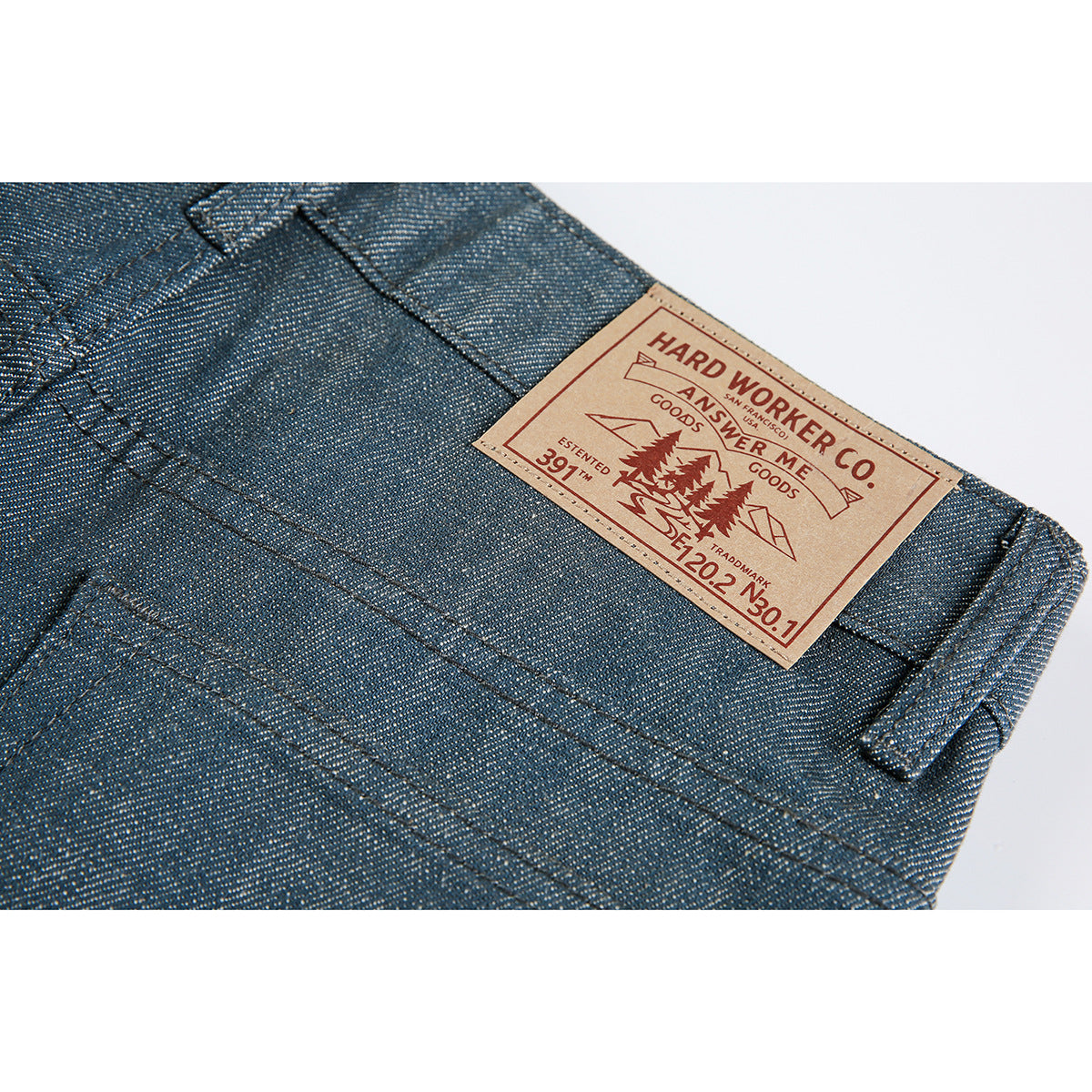 Close-up of a tan branded patch and belt loop on blue-gray trousers.