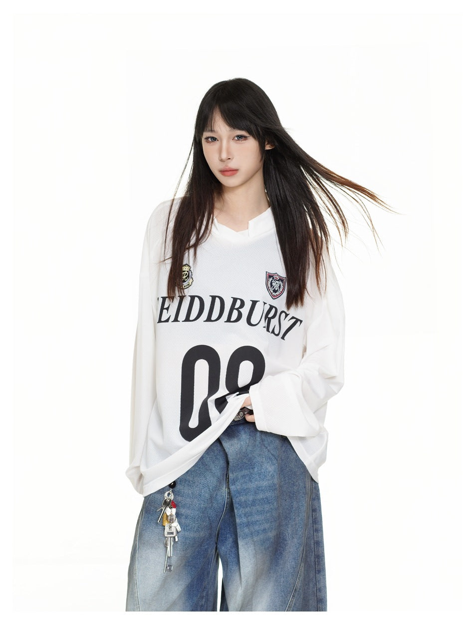Closer view of a model wearing a white oversized long-sleeve jersey with crest patches, black lettering and number 08.