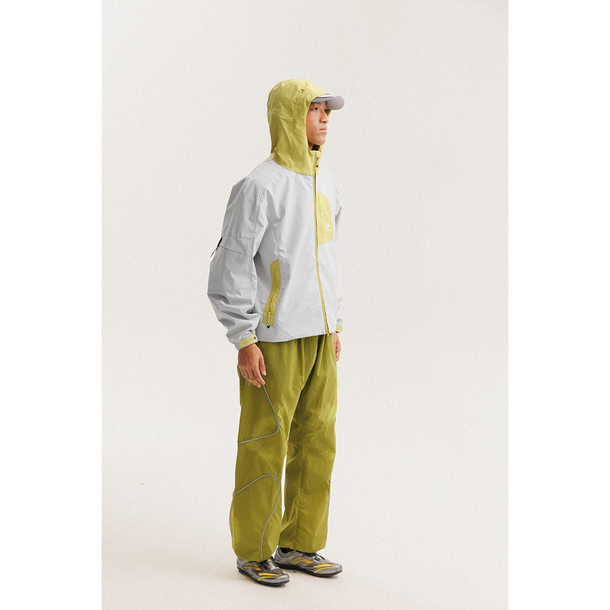Side view of a model wearing a white hooded jacket with yellow-green accents and matching loose trousers.