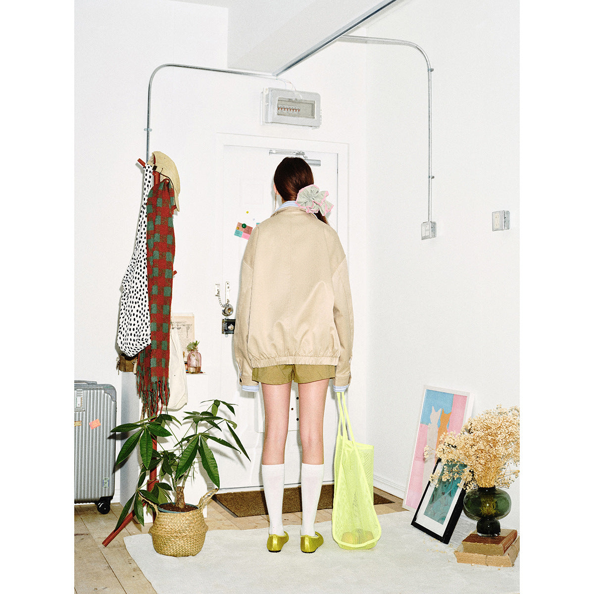 Back view of a model wearing a beige jacket with an elastic hem and striped blue cuffs.
