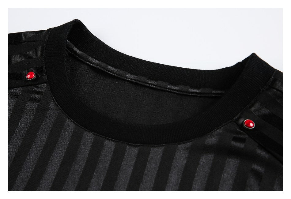 Close-up of a black top's ribbed crew neck, subtle vertical stripes, and red shoulder buttons.