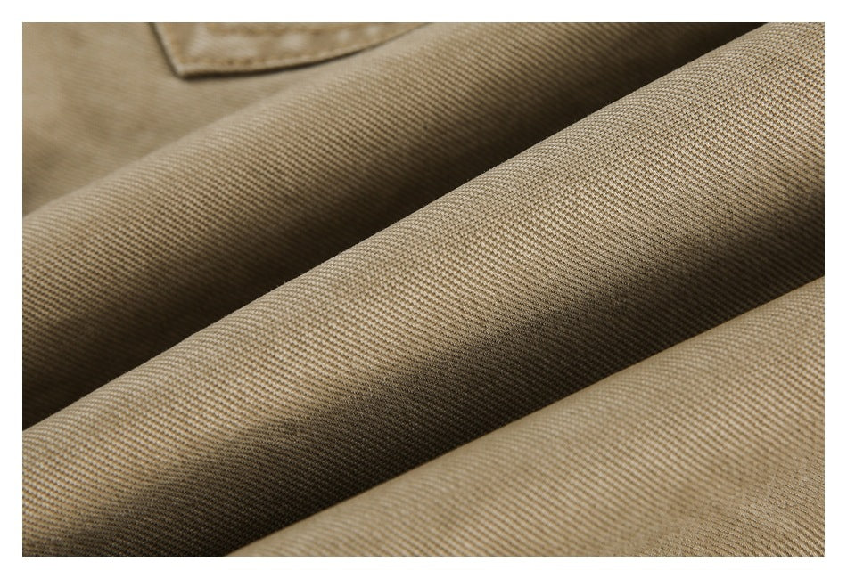 Close-up of tan trouser fabric in soft folds, showing its fine woven texture.