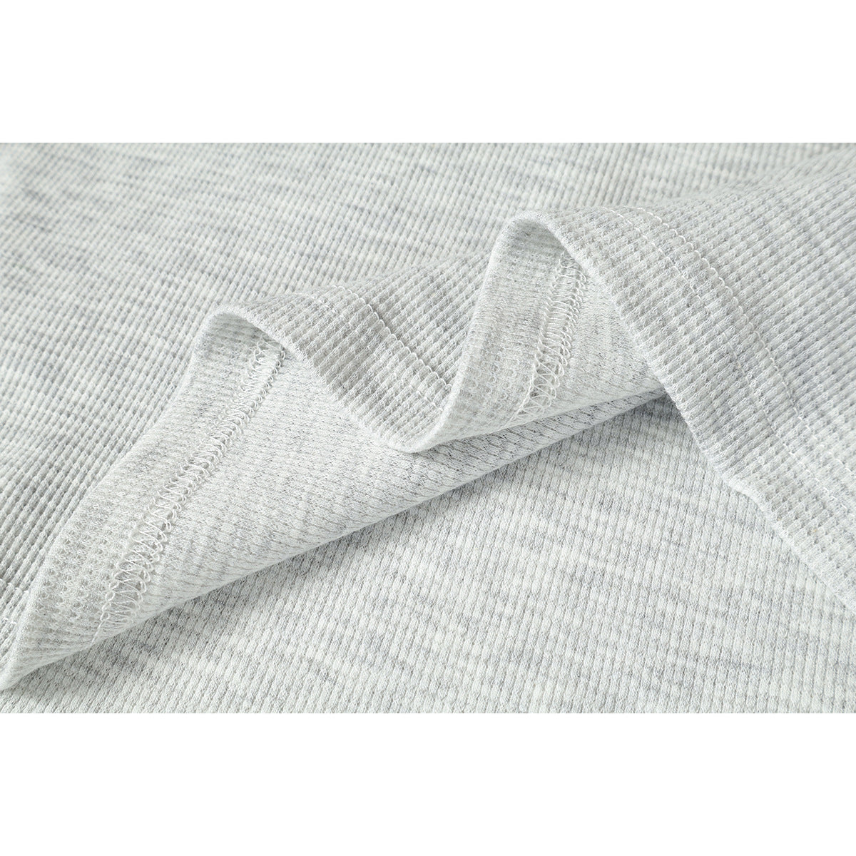 Close-up of light gray ribbed fabric folded to show the reverse side and overlock seam.
