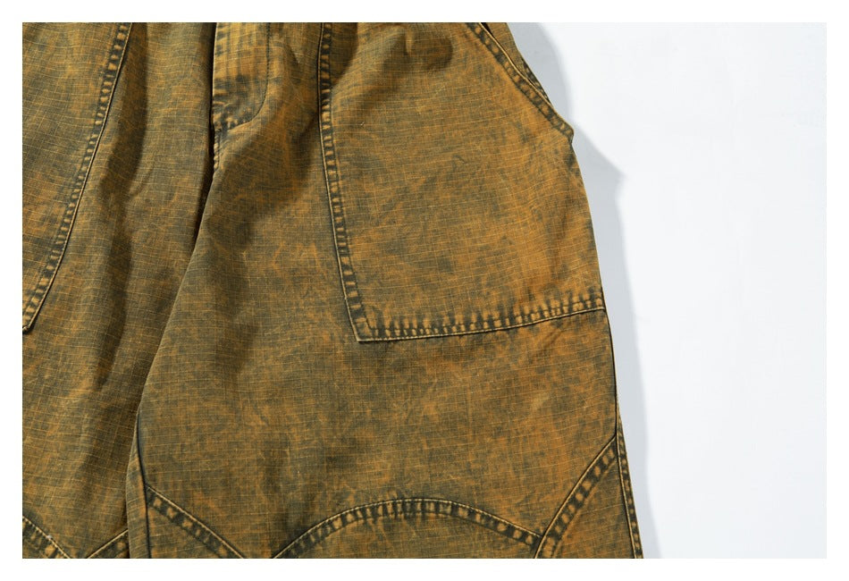 Close-up of ochre-brown mottled pants with a large stitched pocket and curved panel seams.