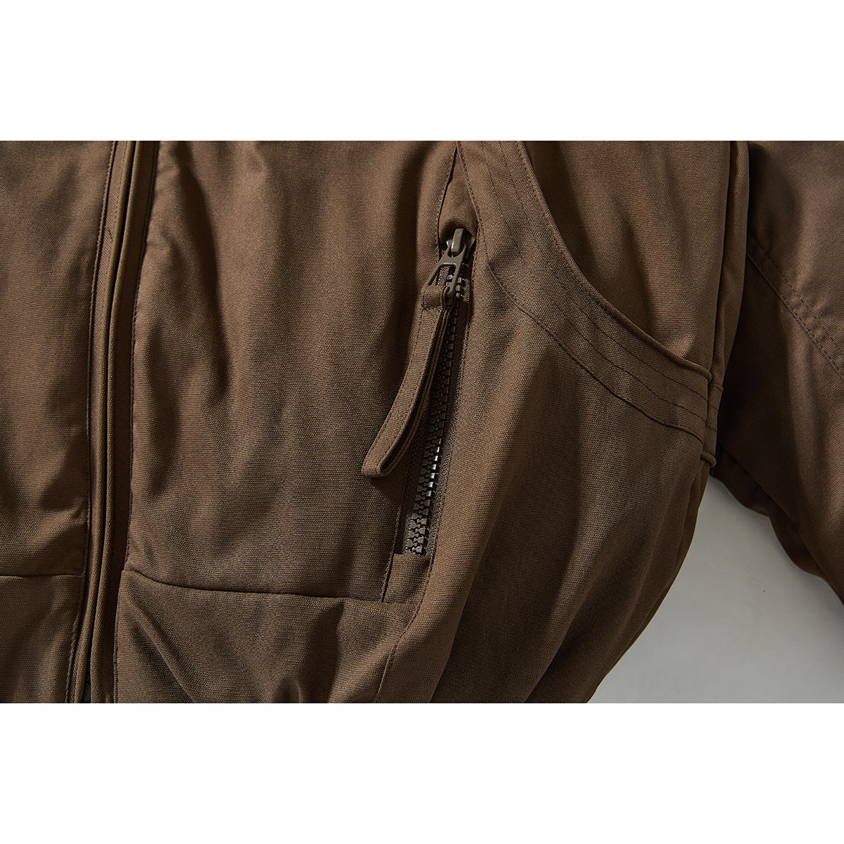 Close-up of a brown jacket’s front with a vertical zip pocket and curved pocket seam.
