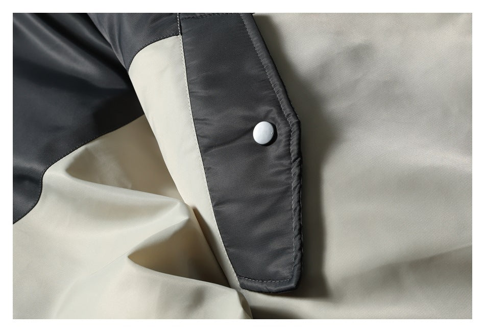 Close-up of a black snap-button flap against the jacket's beige and black panels.