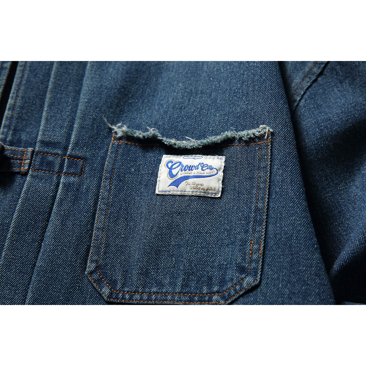 Close-up of a blue denim jacket pocket with a frayed edge and sewn English-script label.