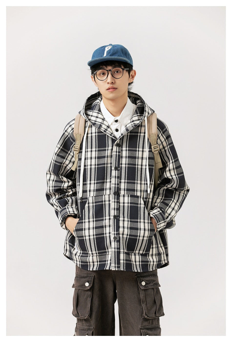 Front view of a model wearing a black-and-white plaid hooded button coat with two front pockets.