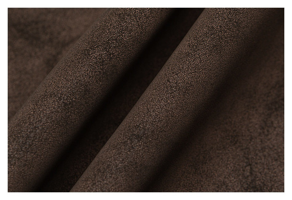 Macro view of the finely textured dark brown garment fabric folded into ridges.