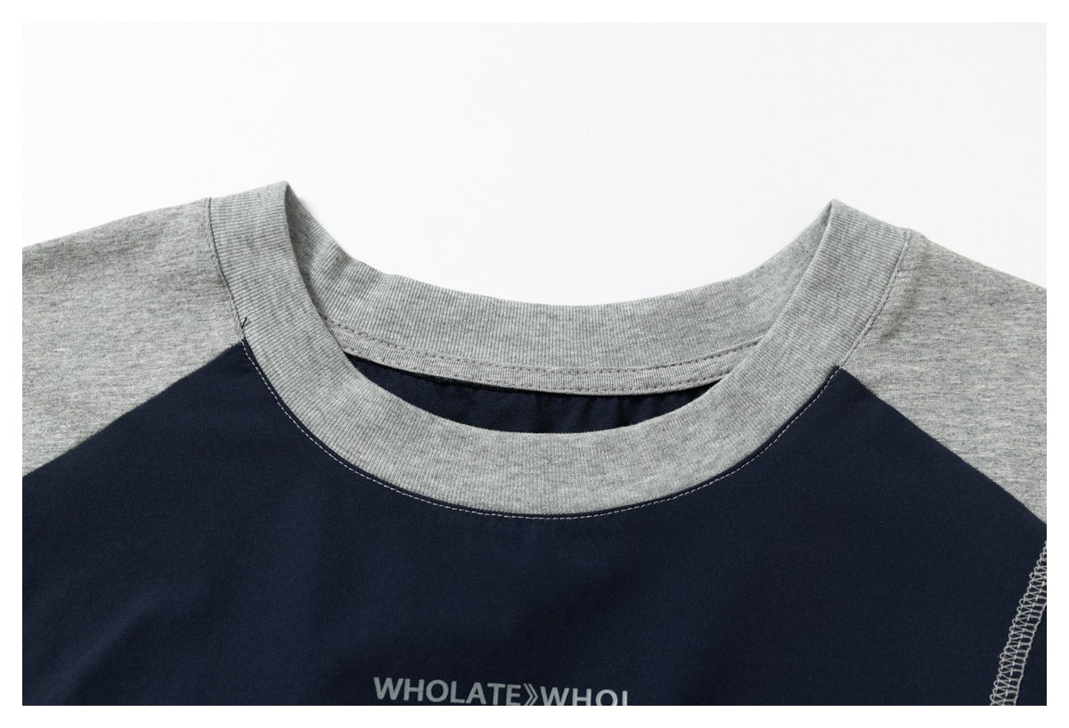 Close-up of a navy shirt with gray raglan shoulders, a ribbed gray crew neck, and partial white chest lettering.