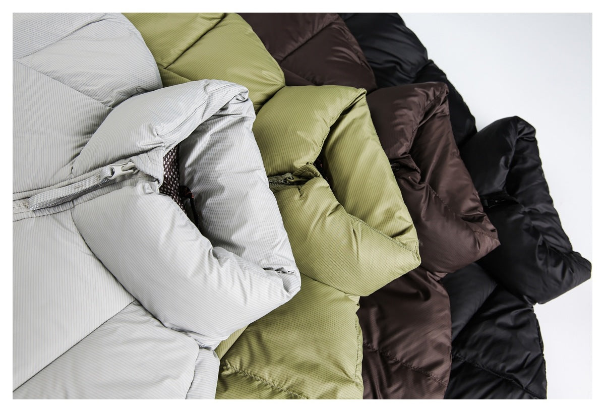 Close-up of light gray, olive, dark brown, and black puffer jackets arranged together.