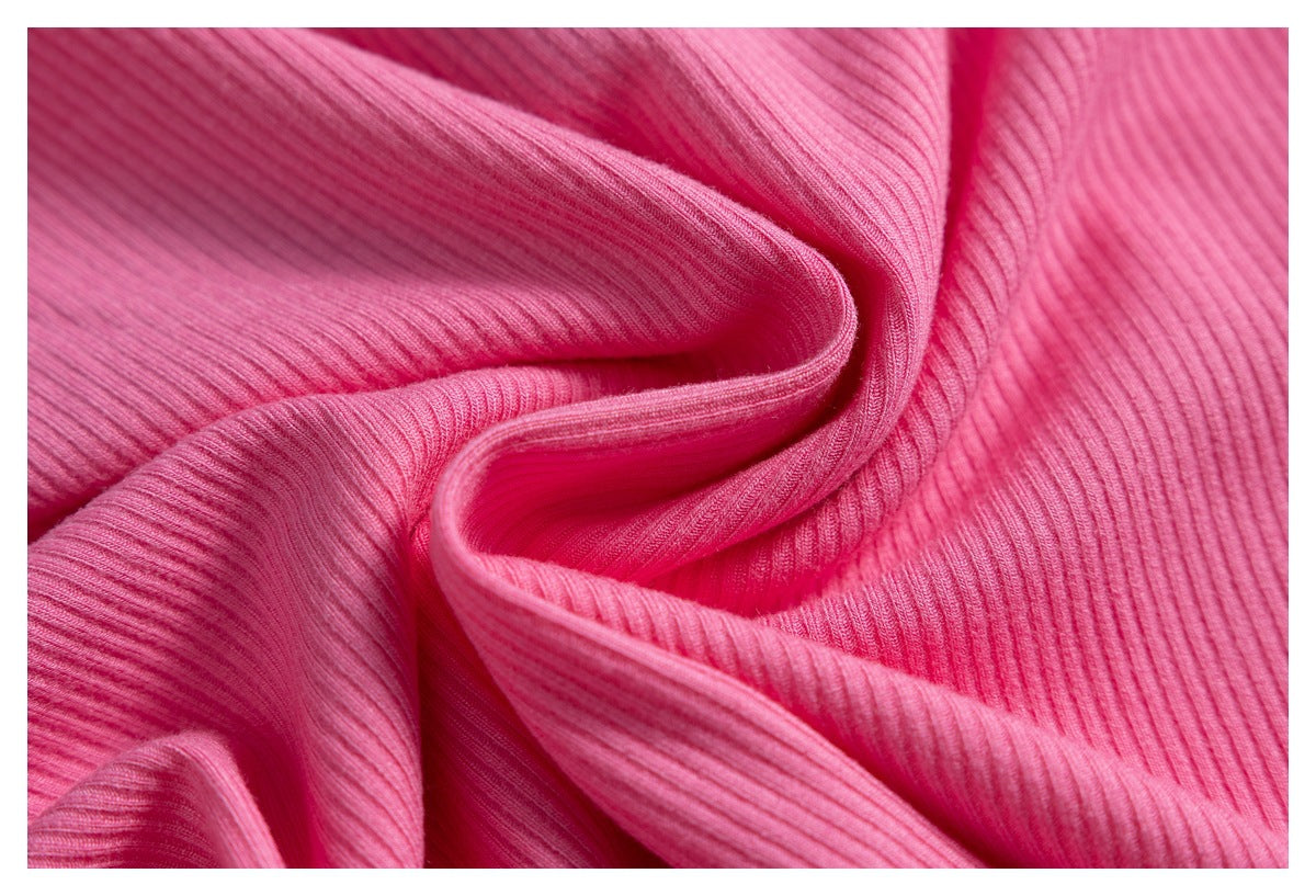 Close-up of soft folds in bright pink ribbed fabric.