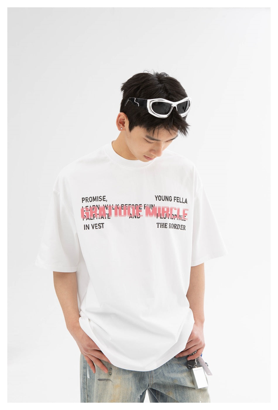 Front view of a model wearing a white oversized T-shirt with layered black and pink text across the chest.