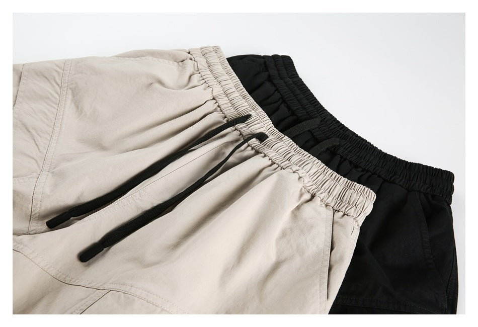 Close-up of beige and black shorts showing gathered elastic waistbands and black drawstrings.