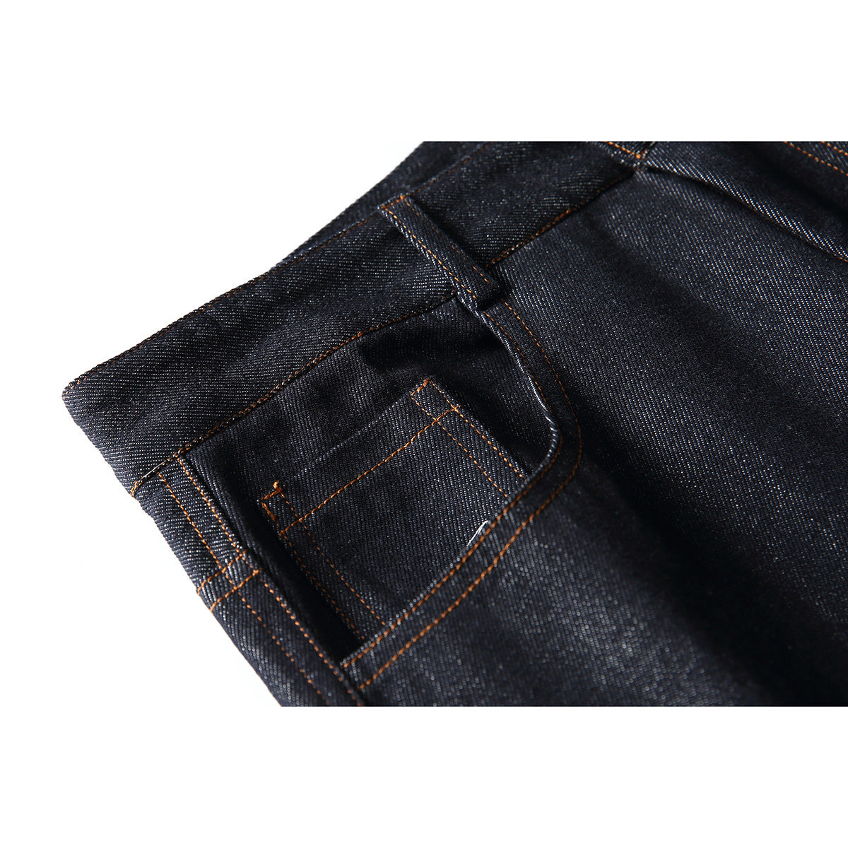 Close-up of dark indigo jeans showing a small pocket, belt loop and orange contrast stitching.