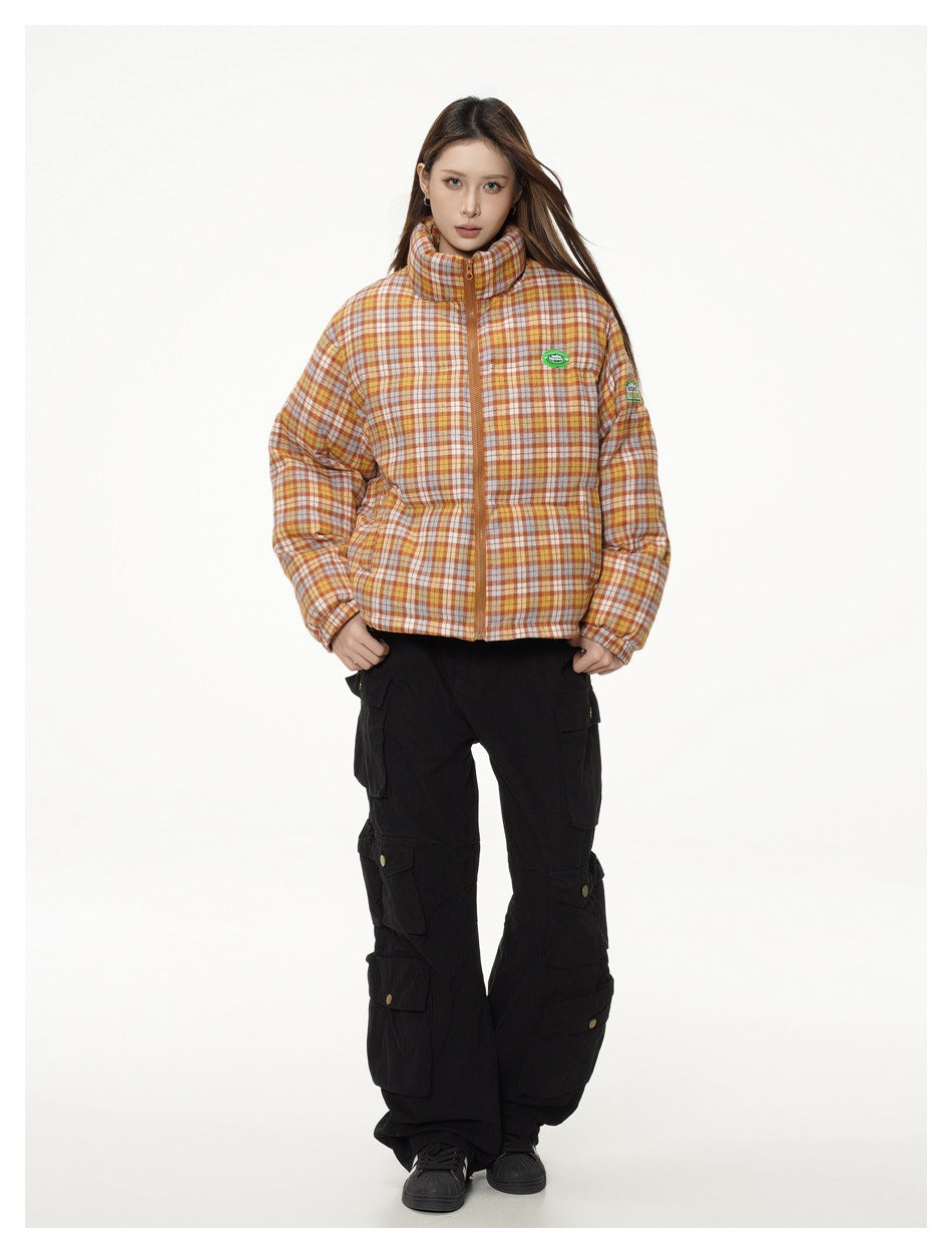 Front view of a model in an orange, cream, and brown plaid puffer jacket with black cargo pants.