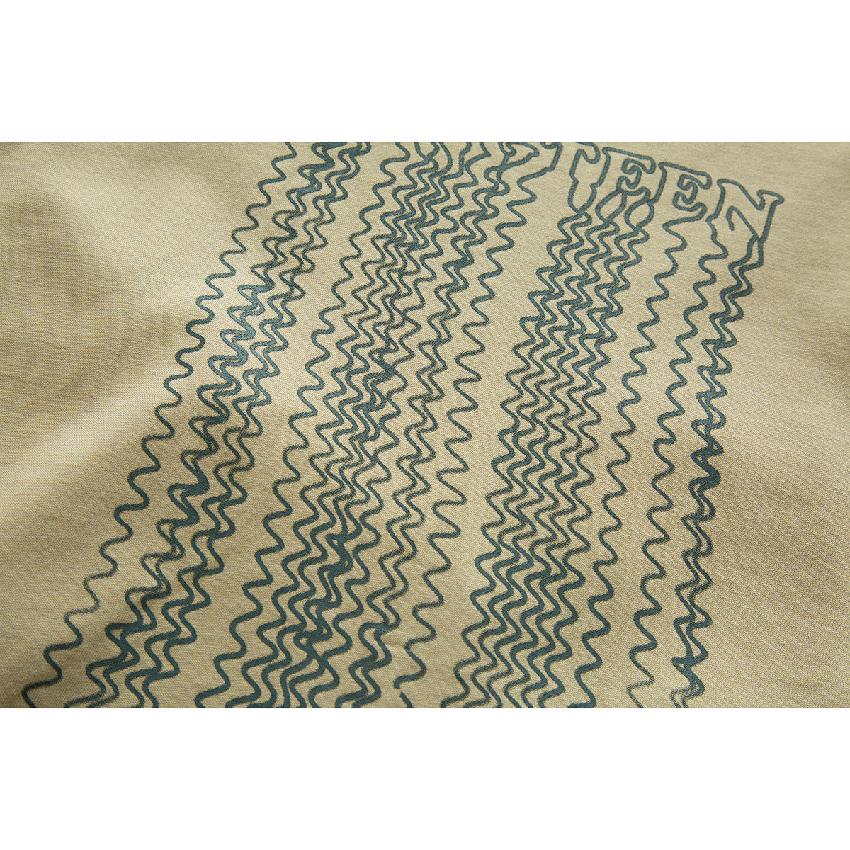 Close-up of dark wavy line artwork and partial lettering printed on beige T-shirt fabric.