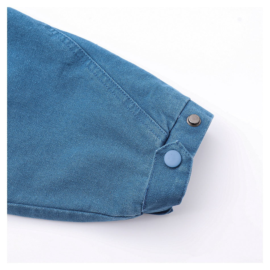 Close-up of a blue woven garment cuff with two snap buttons and visible stitching.