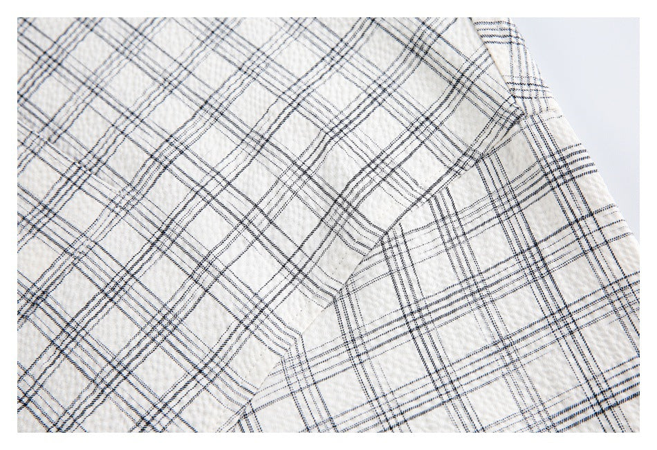 Close-up of off-white garment fabric with a fine black and gray windowpane plaid pattern.