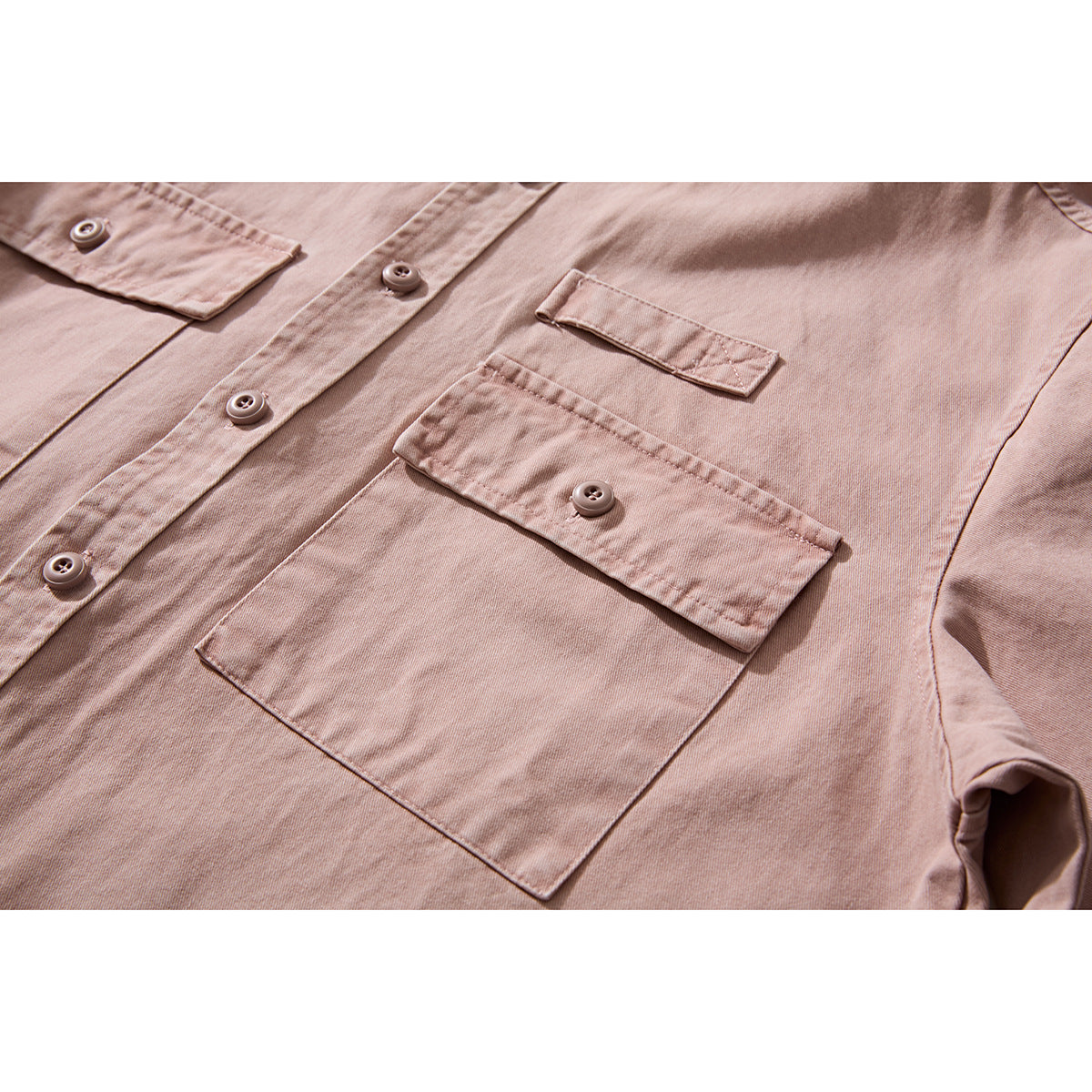 Close-up of a dusty pink shirt front showing its button placket and large button-flap pocket.