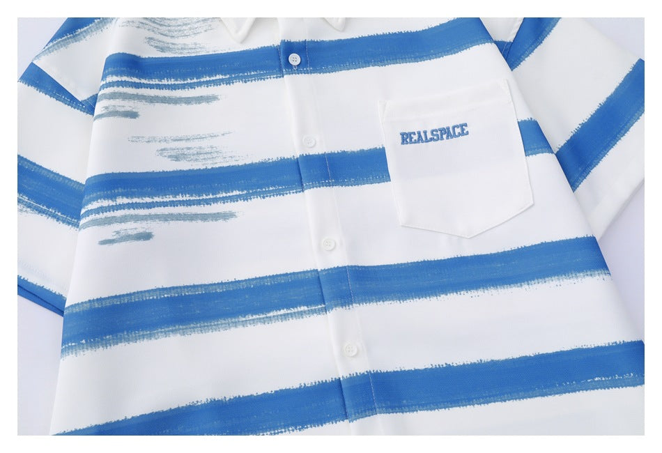 Cropped front view of a white button-up shirt with broad blue brushstroke stripes and an embroidered chest pocket logo.