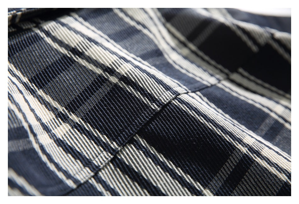 Macro view of the raised woven texture and stitching in the plaid shirt fabric.