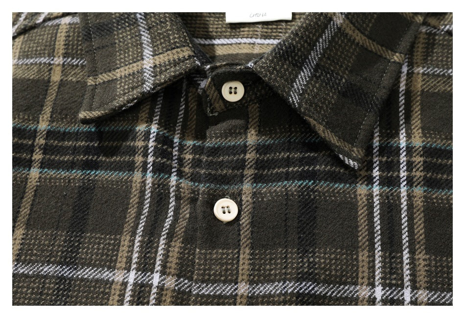 Close-up of the pointed collar and button placket on a dark plaid shirt.