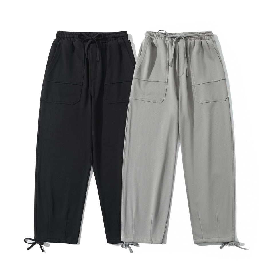Front view of relaxed pants in black and light gray, with elastic drawstring waists, front pockets, and tie cuffs.