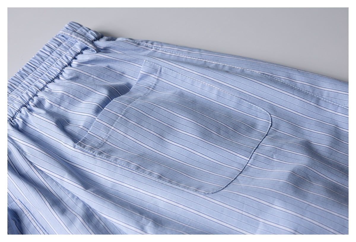 Close-up of a stitched patch pocket on light blue striped shorts.