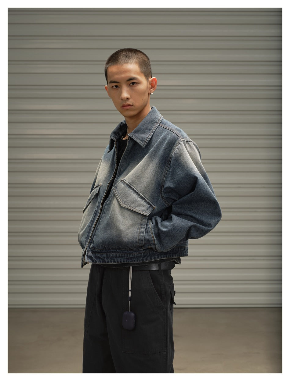 Model in three-quarter pose wearing washed denim jacket with flap pockets and front zip, hand in pocket