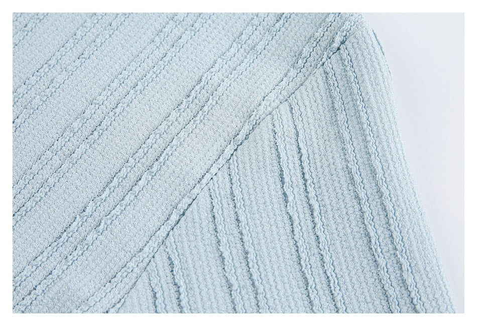 Close-up of a pale blue garment shoulder seam and raised textured fabric.
