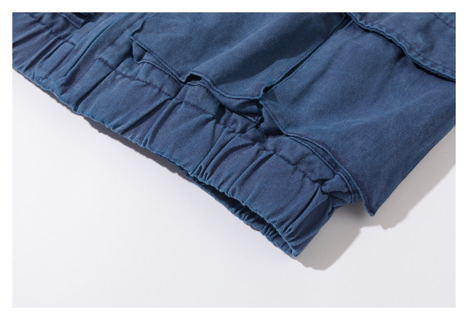 Close-up of gathered elastic waist fabric and overlapping pockets on a blue garment.