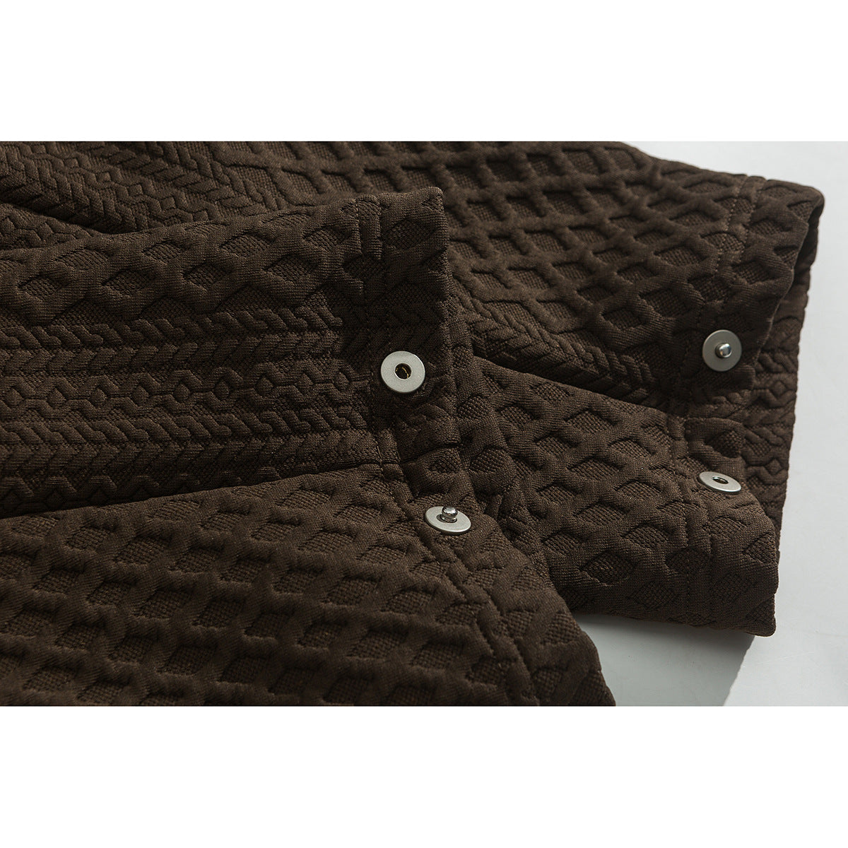 Close-up of a dark brown textured shirt showing its folded placket and metal snap fasteners.