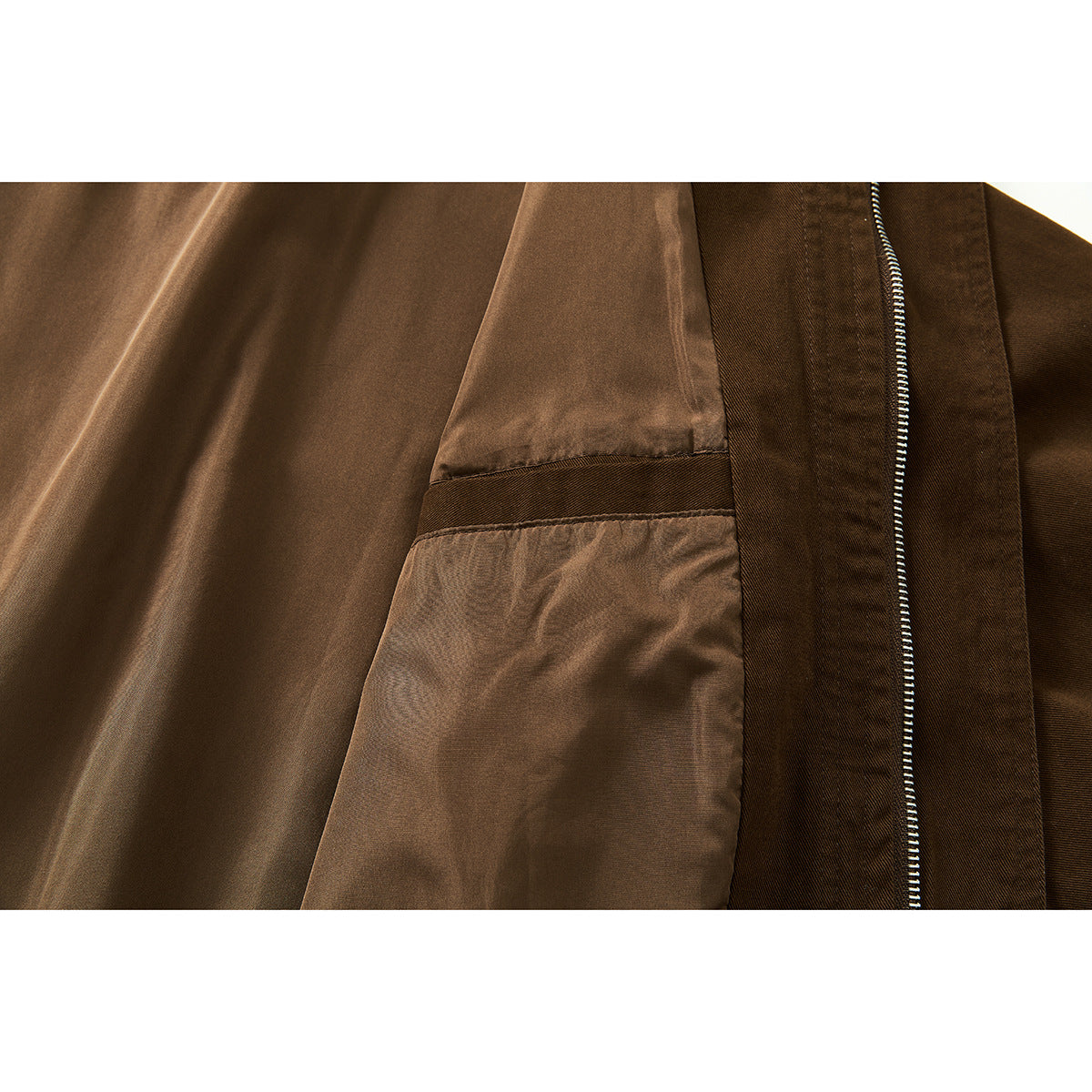Close-up of the brown jacket's smooth inner lining, seam, and silver zipper.