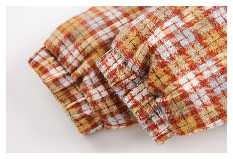 Close-up of orange, cream, pale blue and mustard plaid fabric folded to show a stitched edge.