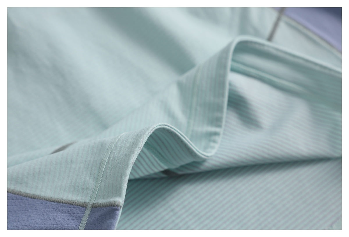 Close-up of the pale aqua top's curved edge and seam, with a lavender color-block section visible.