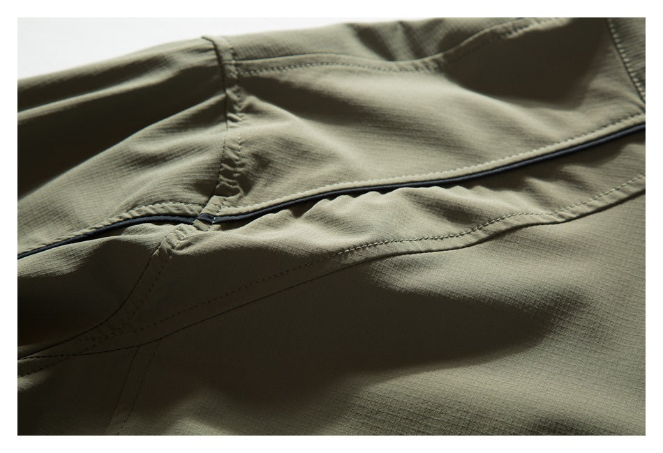 Close-up of olive khaki jacket seams and a narrow black piping detail.