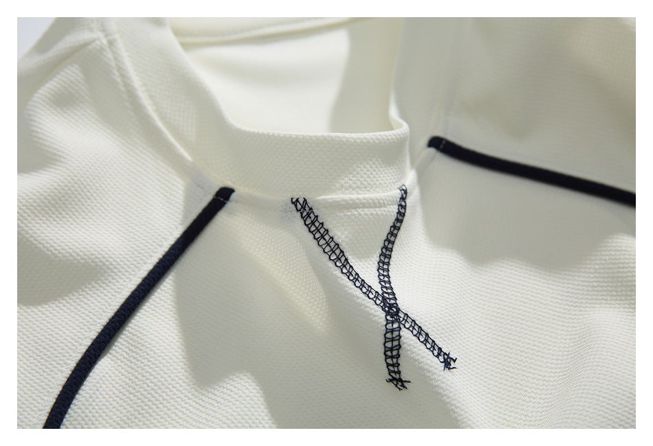 Close-up of an ivory shirt neckline with dark piping and crossed decorative stitching.