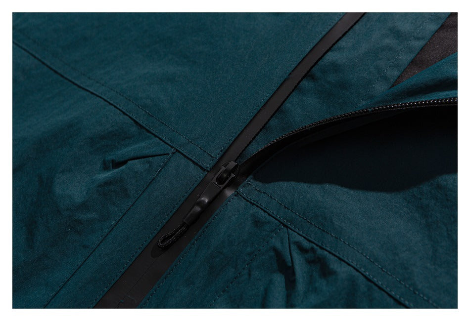 Close-up of a dark teal garment with a black zipper and stitched panel seams.