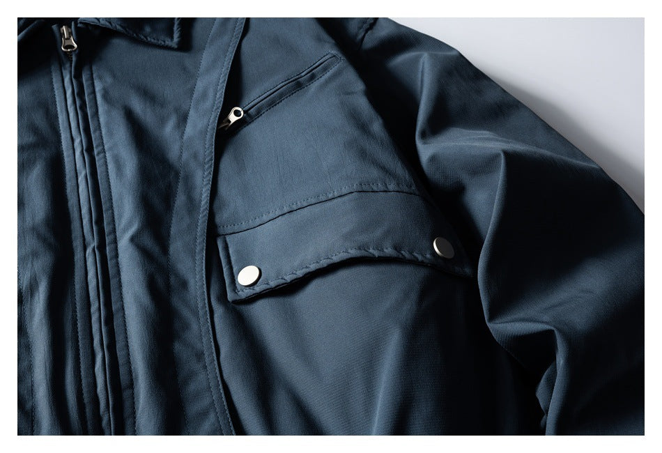 Close-up of a dark navy jacket front with a zip pocket and a flap pocket secured by two snaps.
