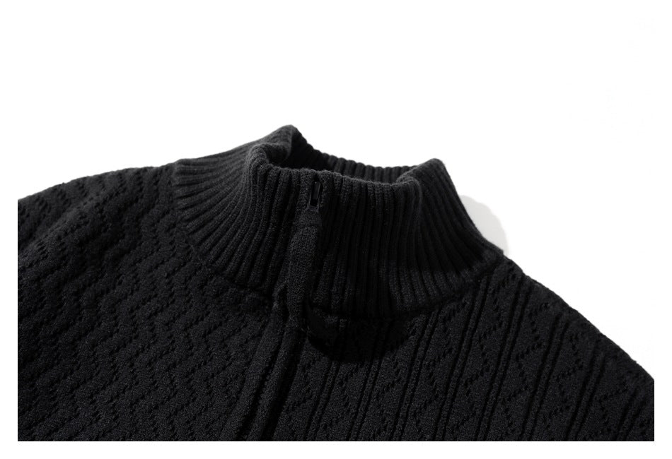 Close-up detail of a black sweater's ribbed stand collar, short zipper, and textured knit pattern.
