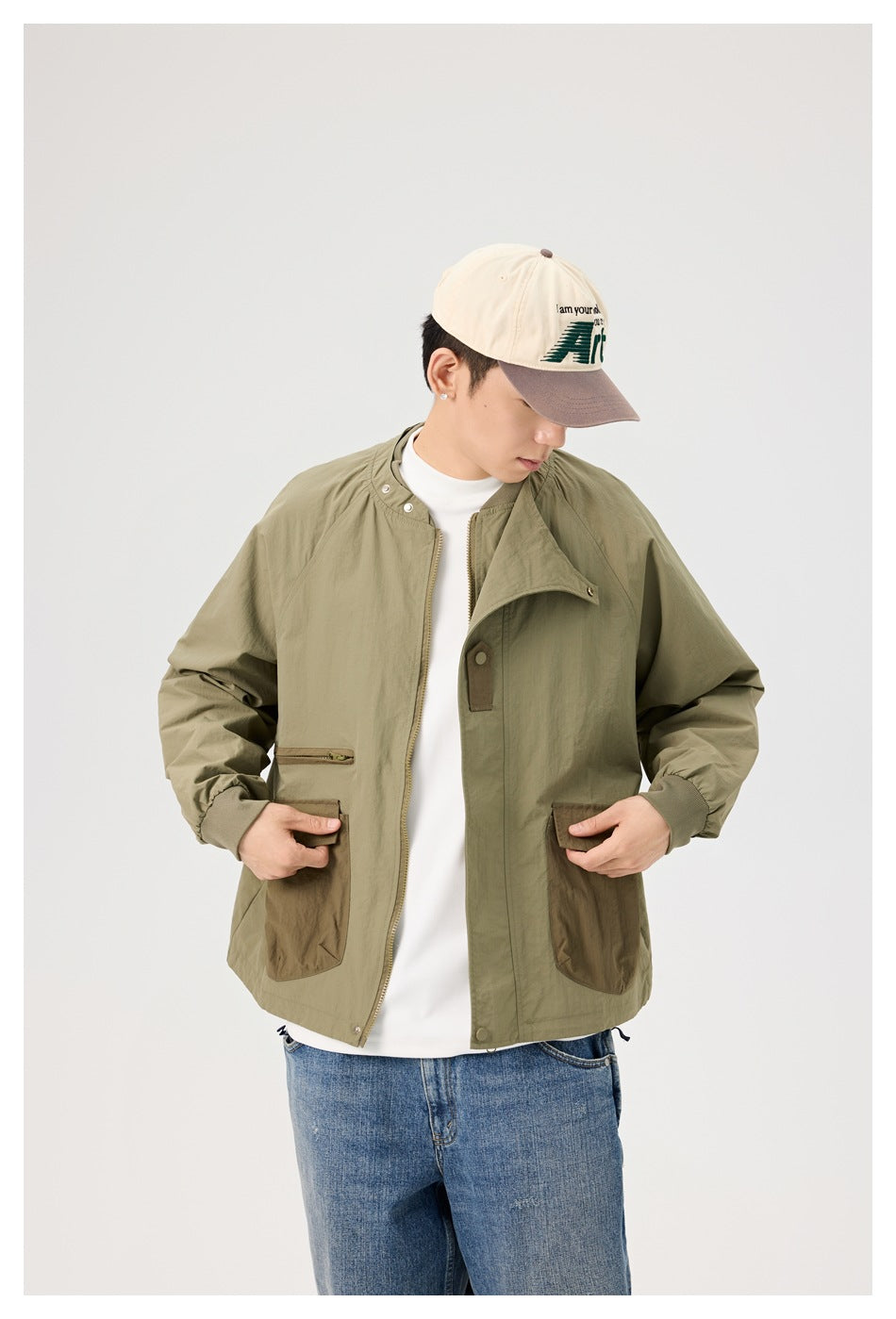 Man modeling an olive jacket with brown pockets, shown from the waist up with the front open.