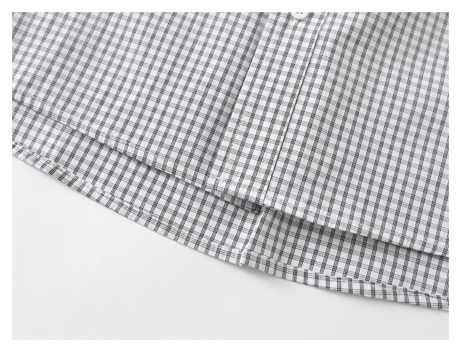 Close-up of the grid-check shirt's button placket and stitched lower hem.