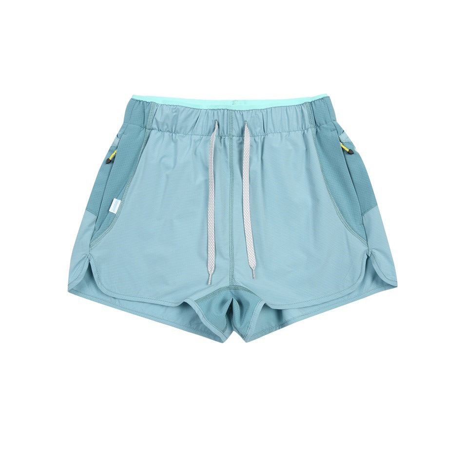 Light blue-teal shorts with white drawstring, darker side panels and zip pockets with yellow pulls, flat lay