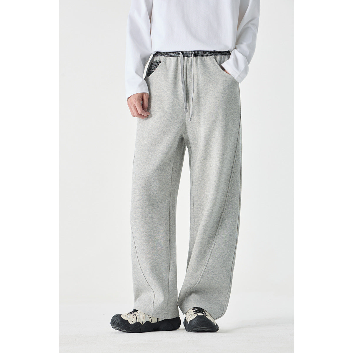 Front view of a model wearing light gray wide-leg pants with a checked elastic waistband, drawstring, and checked pocket