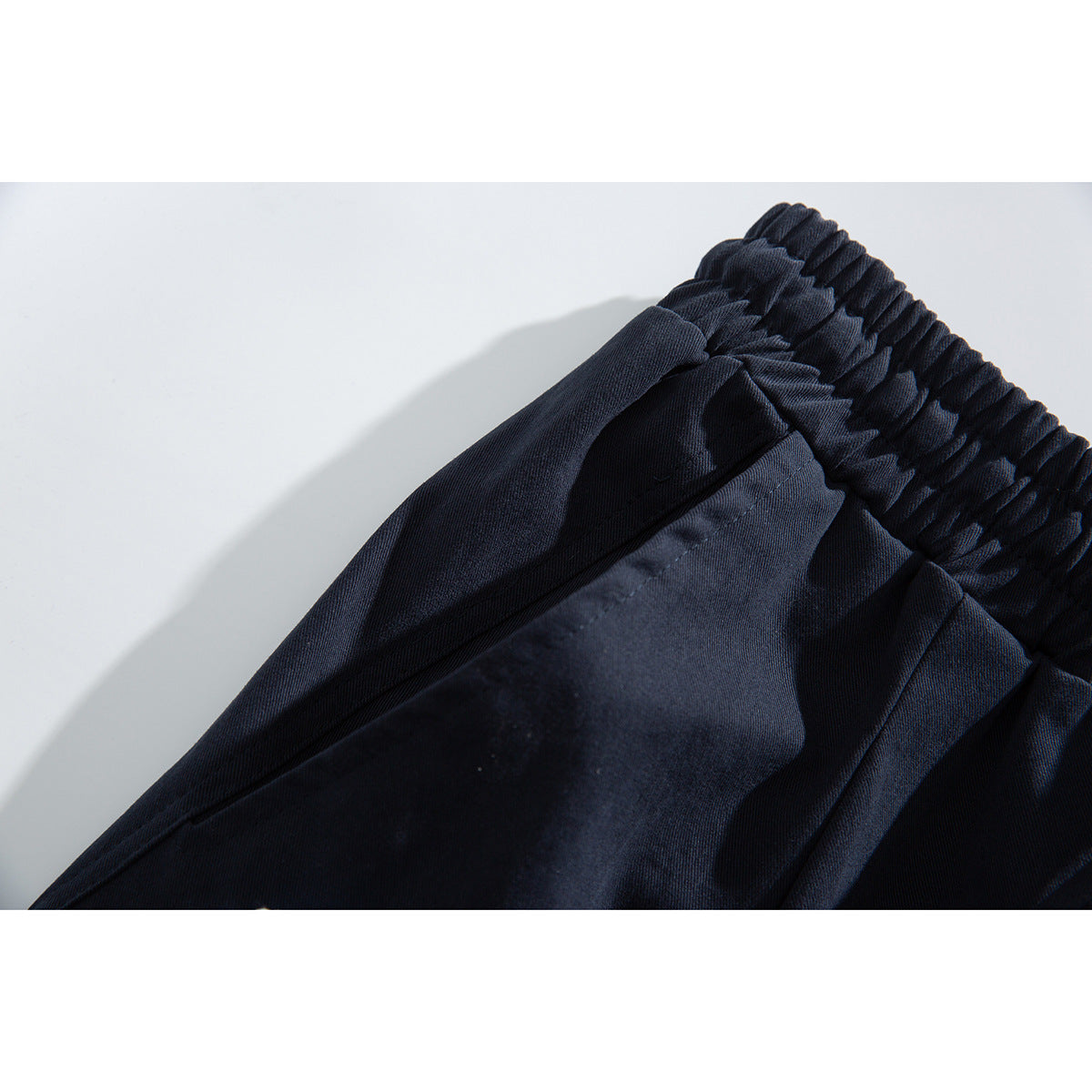 Close-up of dark navy garment fabric and gathered elastic waistband.